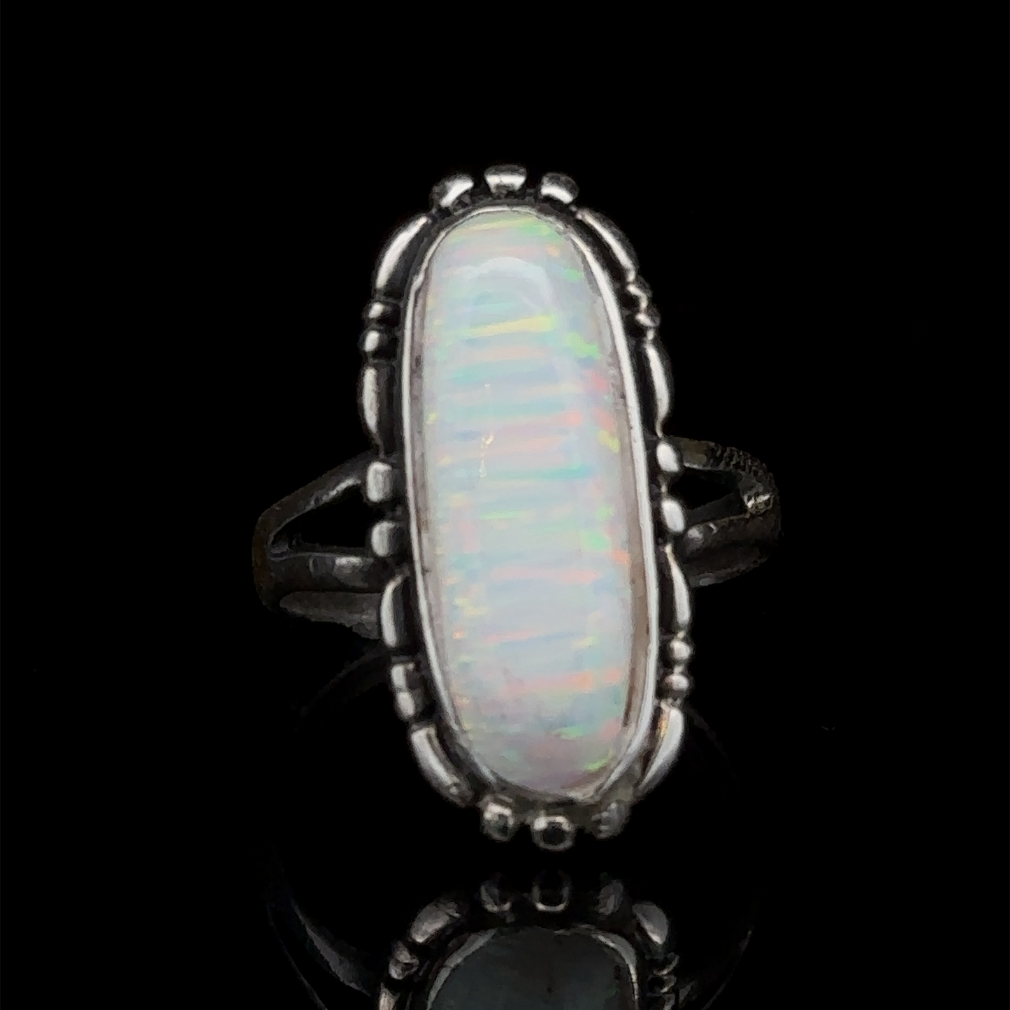 
                  
                    The American Made Oval Opal Ring features a southwestern-styled sterling silver design with an elongated oval lab-created opal showcasing a multi-color iridescent pattern, set against a black background.
                  
                