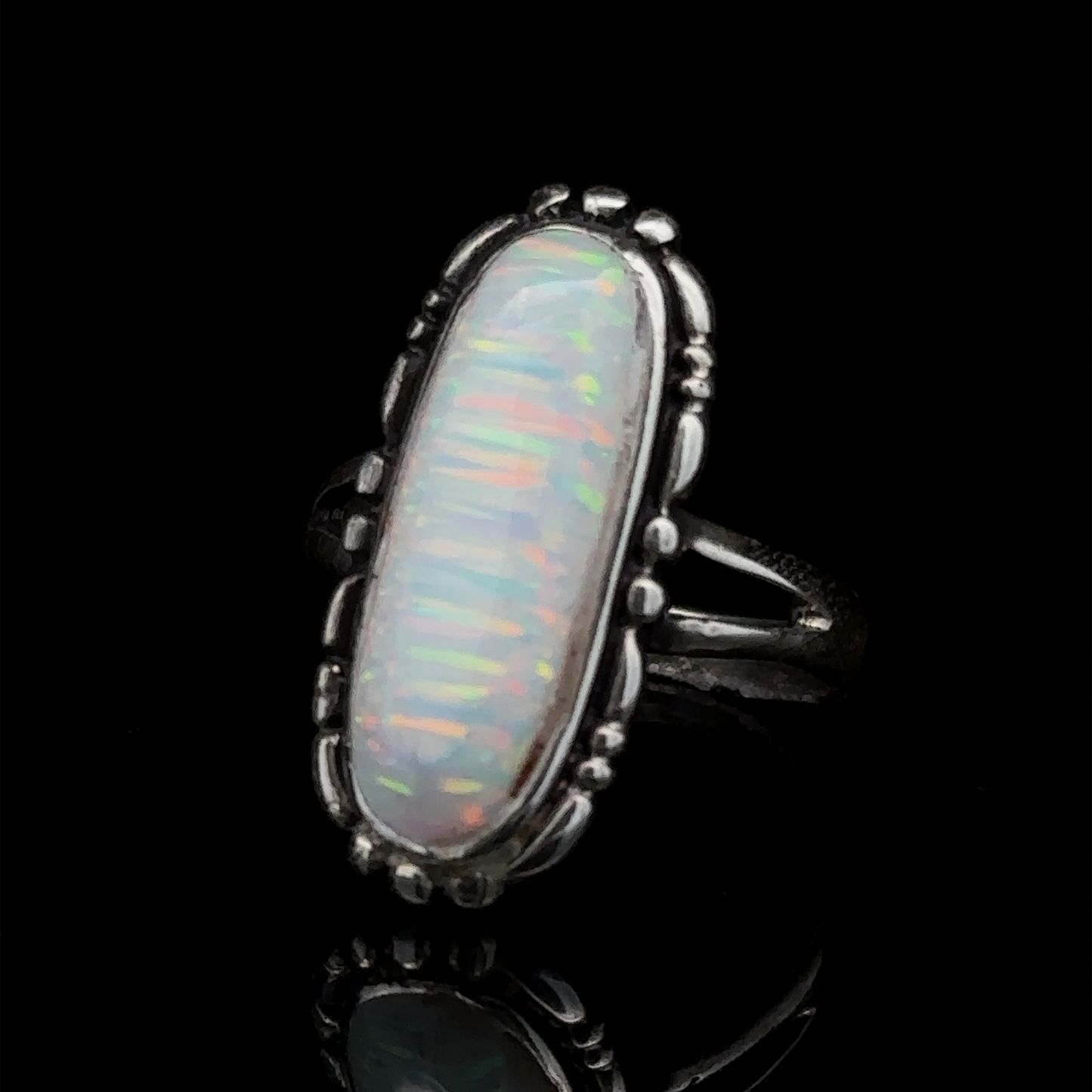 
                  
                    A sterling silver ring featuring an elongated, lab-created opal gemstone with iridescent colors, placed against a black background.

Adjusted Sentence: An American Made Oval Opal Ring featuring an elongated, lab-created opal gemstone with iridescent colors, placed against a black background.
                  
                