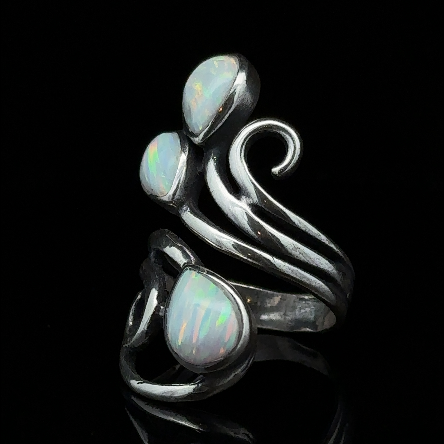 
                  
                    A Stunning Wrap-Around Opal Ring featuring three white opal stones set in a swirling design against a black background.
                  
                