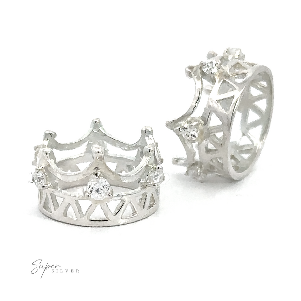 Two sterling silver crown-shaped rings with intricate designs and small cubic zirconia gemstones are displayed. The Cubic Zirconia Crown Pendant features openwork patterns and decorative elements. A small 