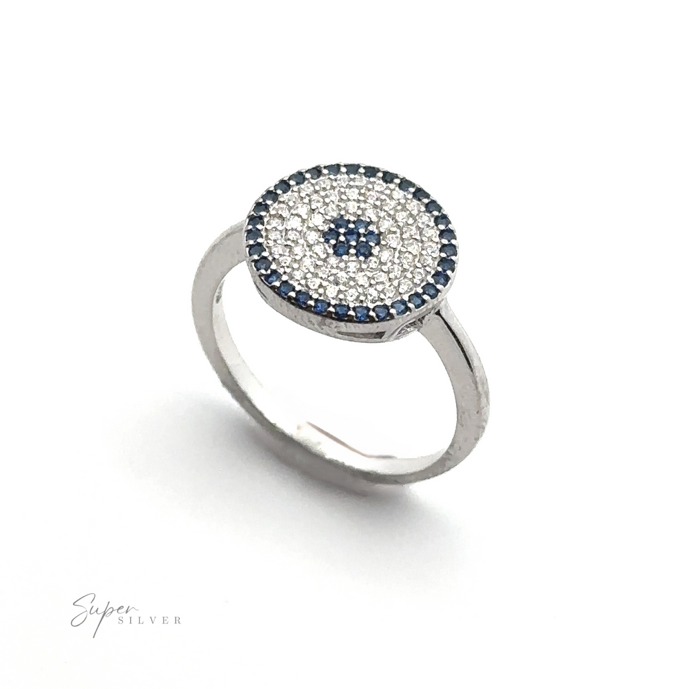 
                  
                    A Cubic Zirconia Evil Eye Ring with a round face, adorned with small white and blue gemstones arranged in concentric circles, creates an elegant evil eye ring design.
                  
                