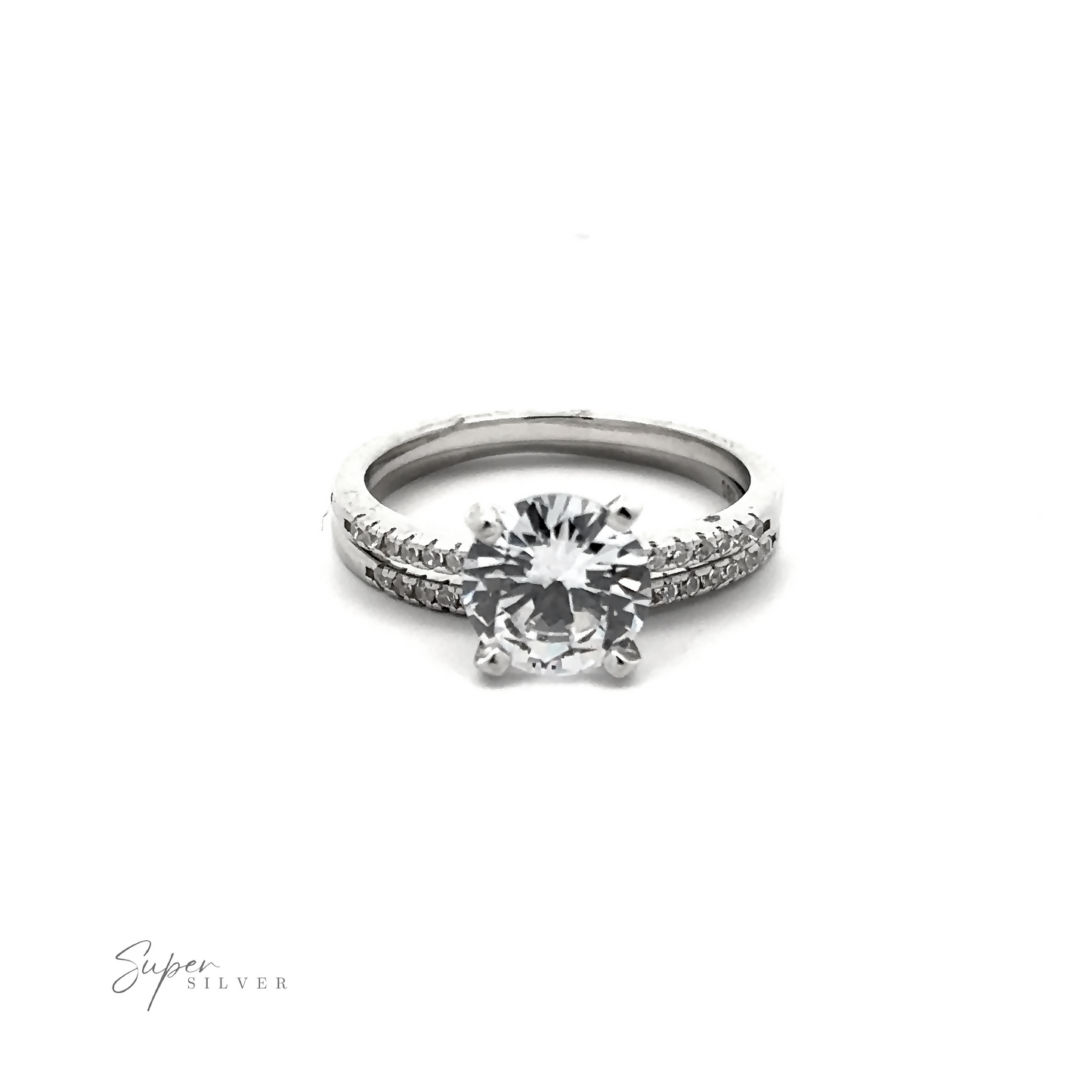 
                  
                    A Round Solitaire Wedding Band Set made of sterling silver, featuring a large round solitaire diamond with smaller pave accents embedded along the band. The words "Super Silver" are visible in the lower left corner.
                  
                