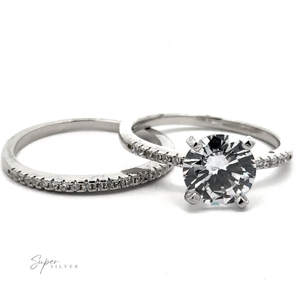 A set of two sterling silver rings with diamonds: one is a plain band with small pave accents, and the other showcases a large round diamond in a solitaire setting. Text reads 