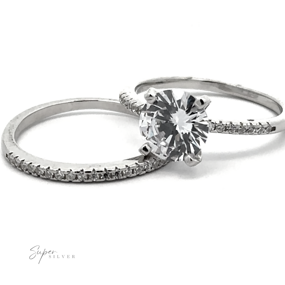 Two sterling silver rings are shown, one with a large round solitaire diamond in a prong setting and the other with pave accents along the band. The logo "Round Cubic Zirconia Wedding Set Ring" is in the bottom left corner.