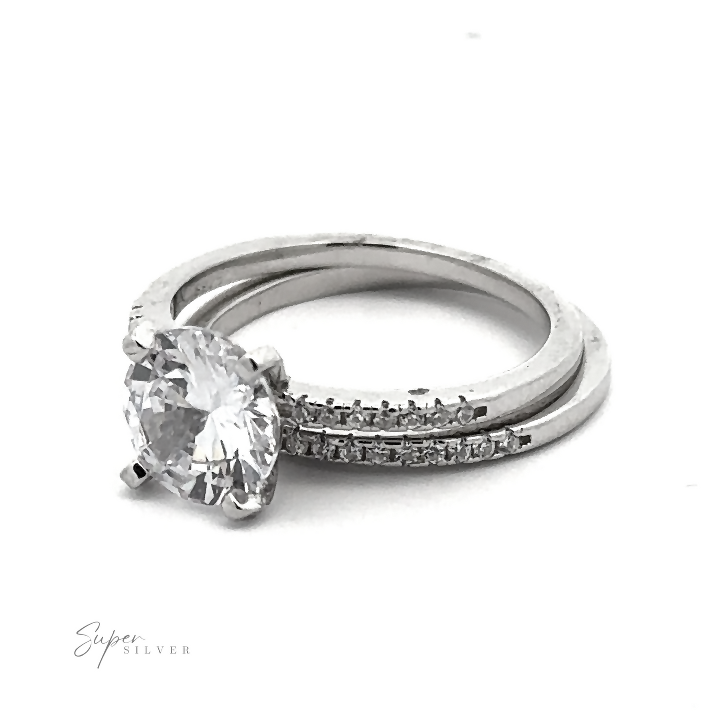 
                  
                    A Round Cubic Zirconia Wedding Set Ring features a large round center diamond, paired with a matching wedding band adorned with pave accents. "Super Silver" is faintly visible in the bottom left corner.
                  
                