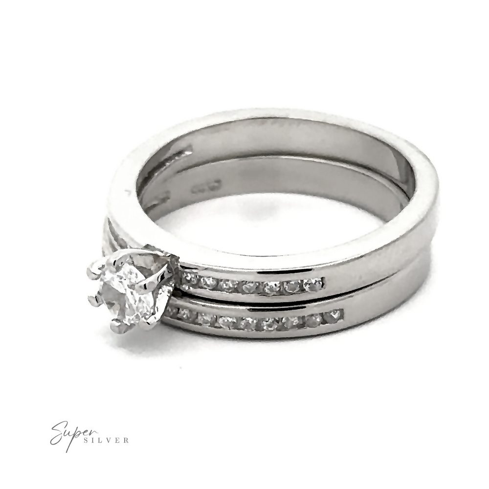 
                  
                    A Brilliant Round Cubic Zirconia Wedding Ring Set with a prominent round diamond and a matching wedding band featuring small embedded diamonds, both marked "Super Silver," boast a Sterling Silver Rhodium Finish for added shine.
                  
                