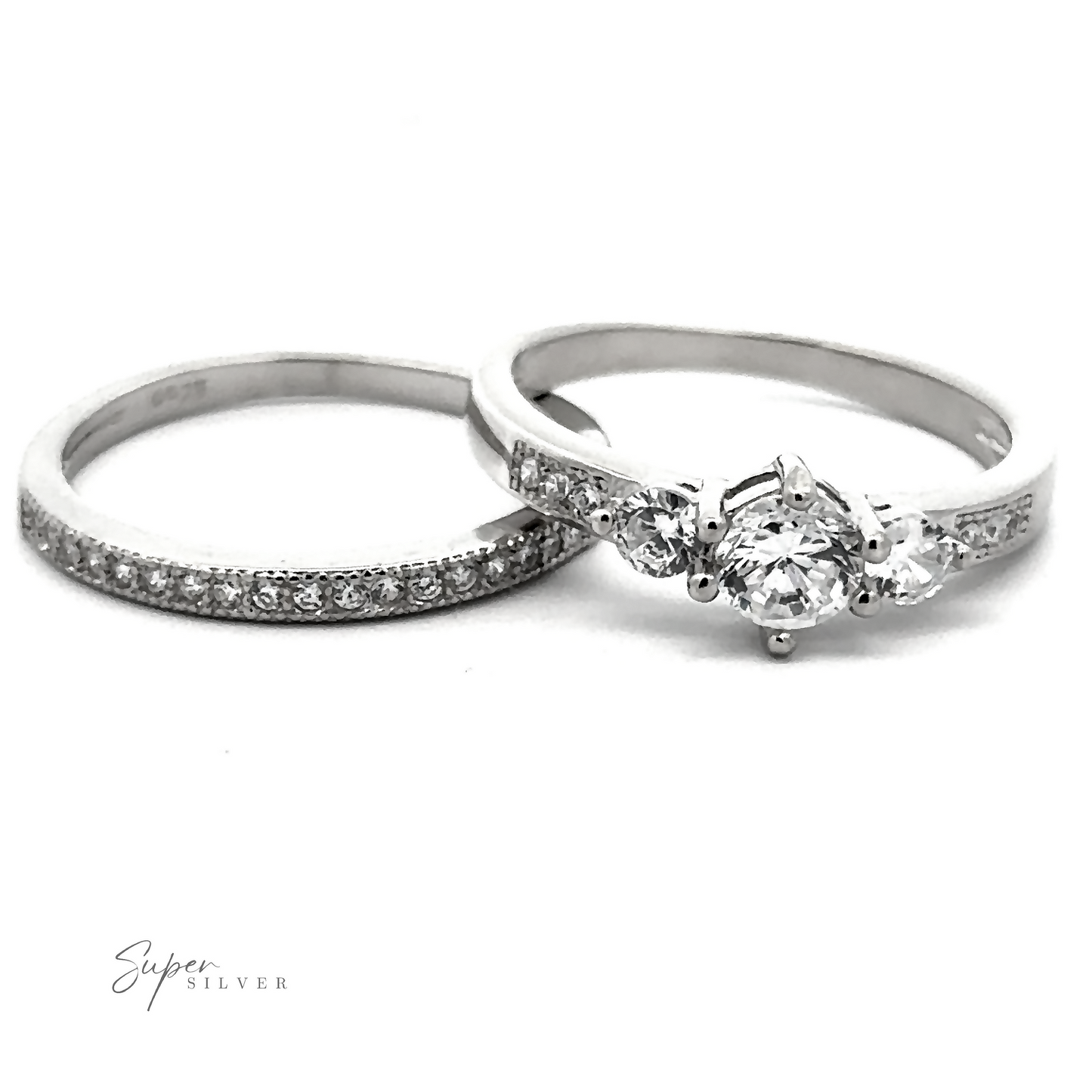Two silver rings, one showcasing a row of small, high-quality cubic zirconia stones and another featuring a central round diamond flanked by two smaller diamonds, displayed on a white background. "Round Cubic Zirconia Wedding Band Set" is written in the bottom left corner.