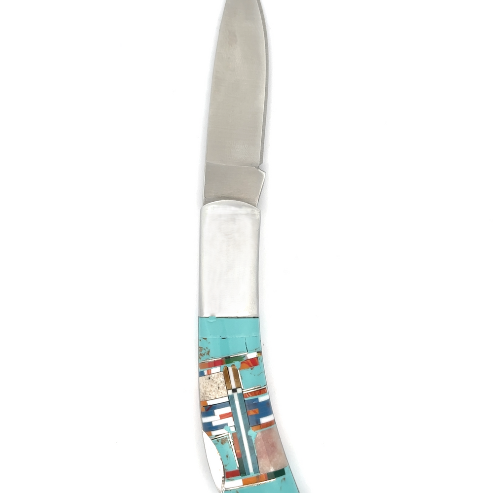 
                  
                    The Intricate Inlay Southwest Pocket Knife is a folding knife featuring a stainless steel blade and a handle decorated with turquoise inlay, exhibiting a vibrant geometric design in the traditional Southwest style.
                  
                