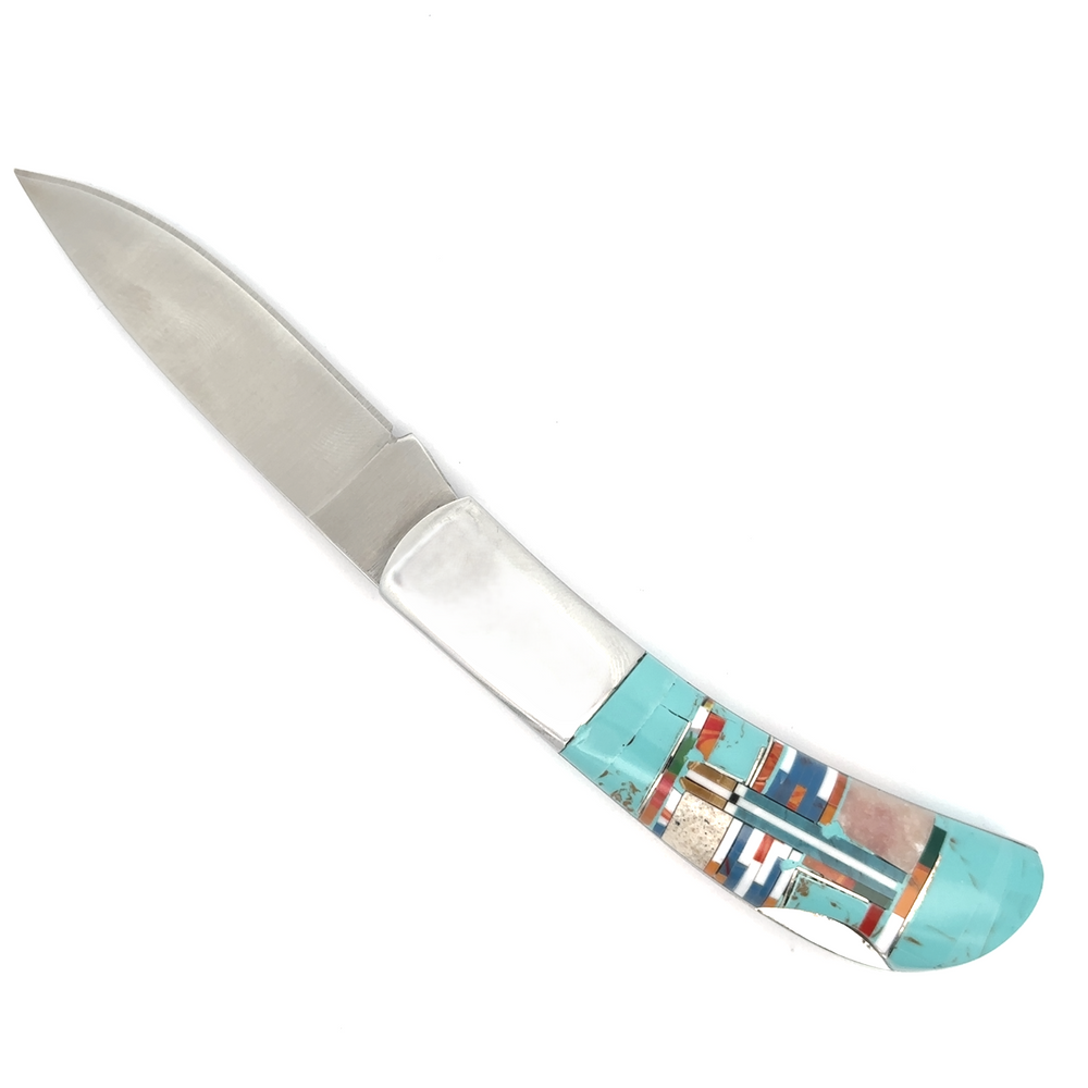 
                  
                    Explore the Intricate Inlay Southwest Pocket Knife, a handcrafted piece boasting a polished metal blade and a vibrant handle adorned with turquoise inlay, perfectly capturing the essence of Southwest style.
                  
                