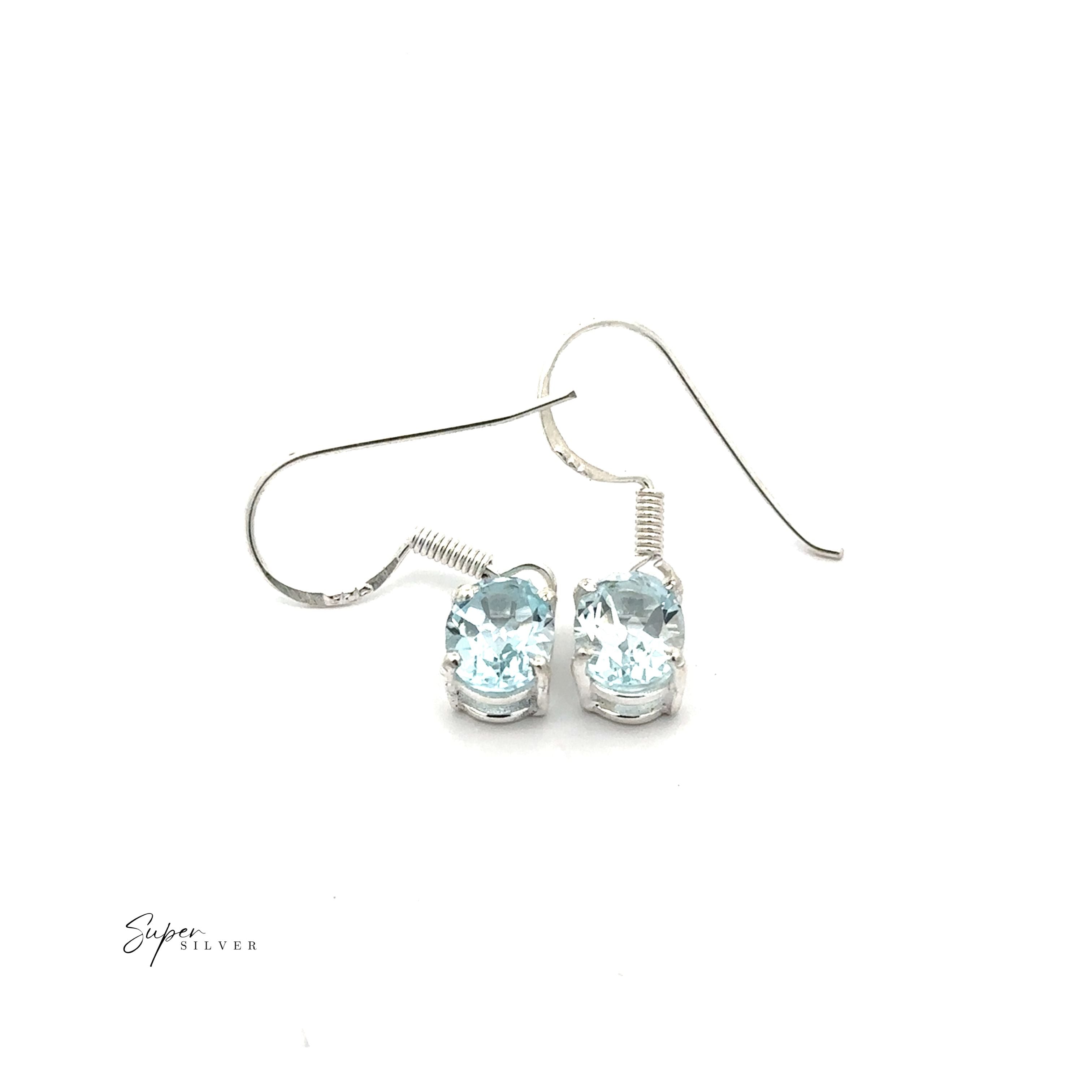 The Brilliant Oval Gemstone Earrings are sterling silver prong-set studs featuring light blue gemstones, shown on a white background.