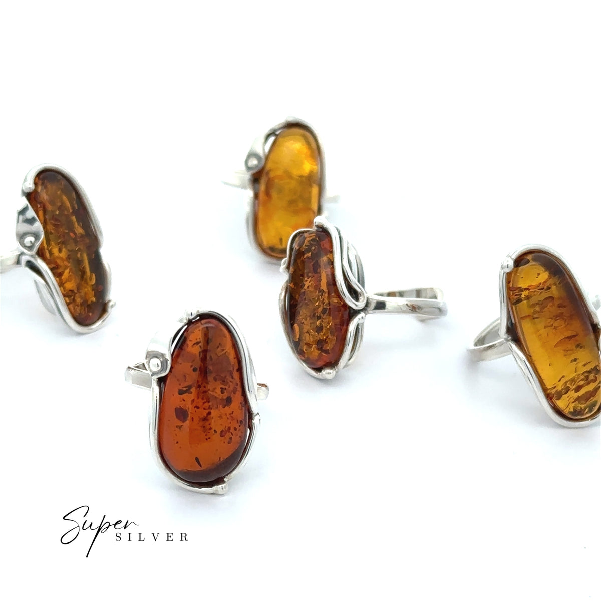 Five silver rings with large, irregular amber stones in Calla Lily settings are displayed on a white background, each showcasing the organic beauty of Baltic Amber. The text “Super Silver” appears in the lower left corner, highlighting these stunning Baltic Amber Rings with their unique Bohemian style.