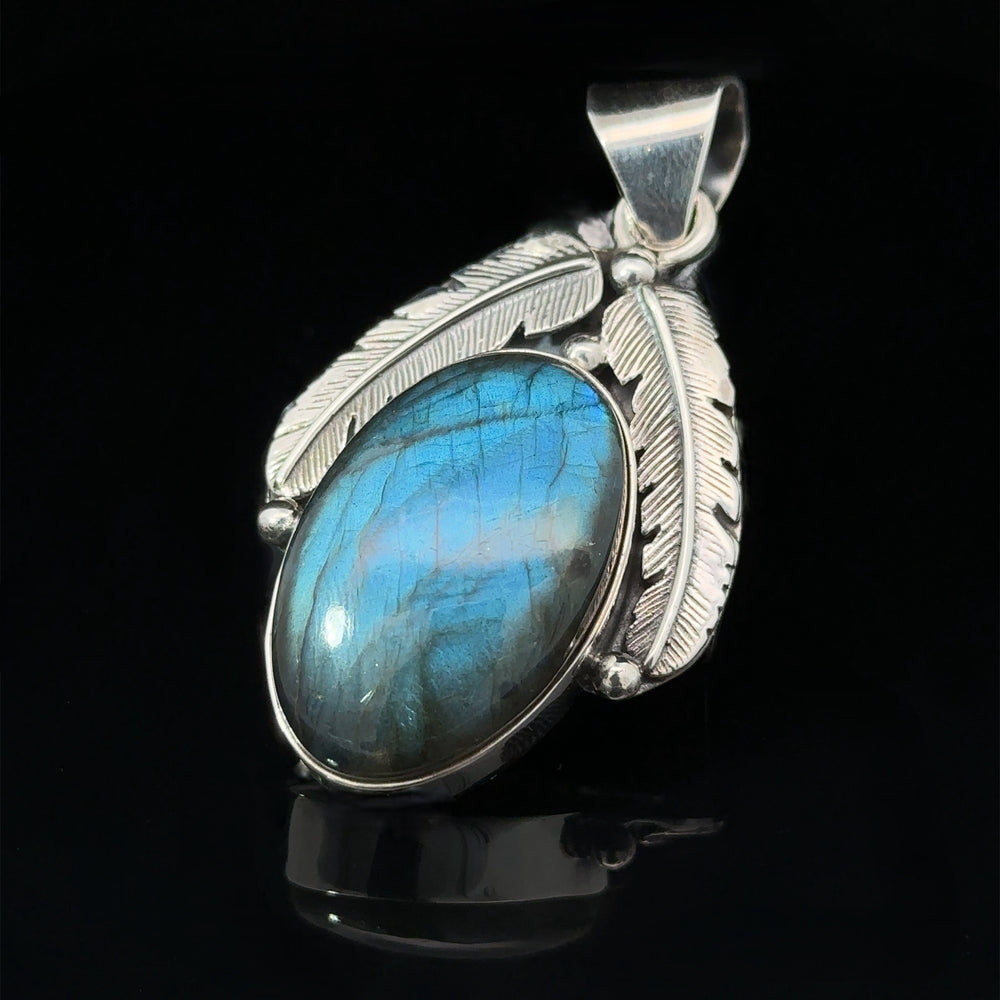 
                  
                    A Beautiful Southwest Stone Pendant featuring a mesmerizing blue labradorite stone is adorned with detailed feather designs on a black background.
                  
                