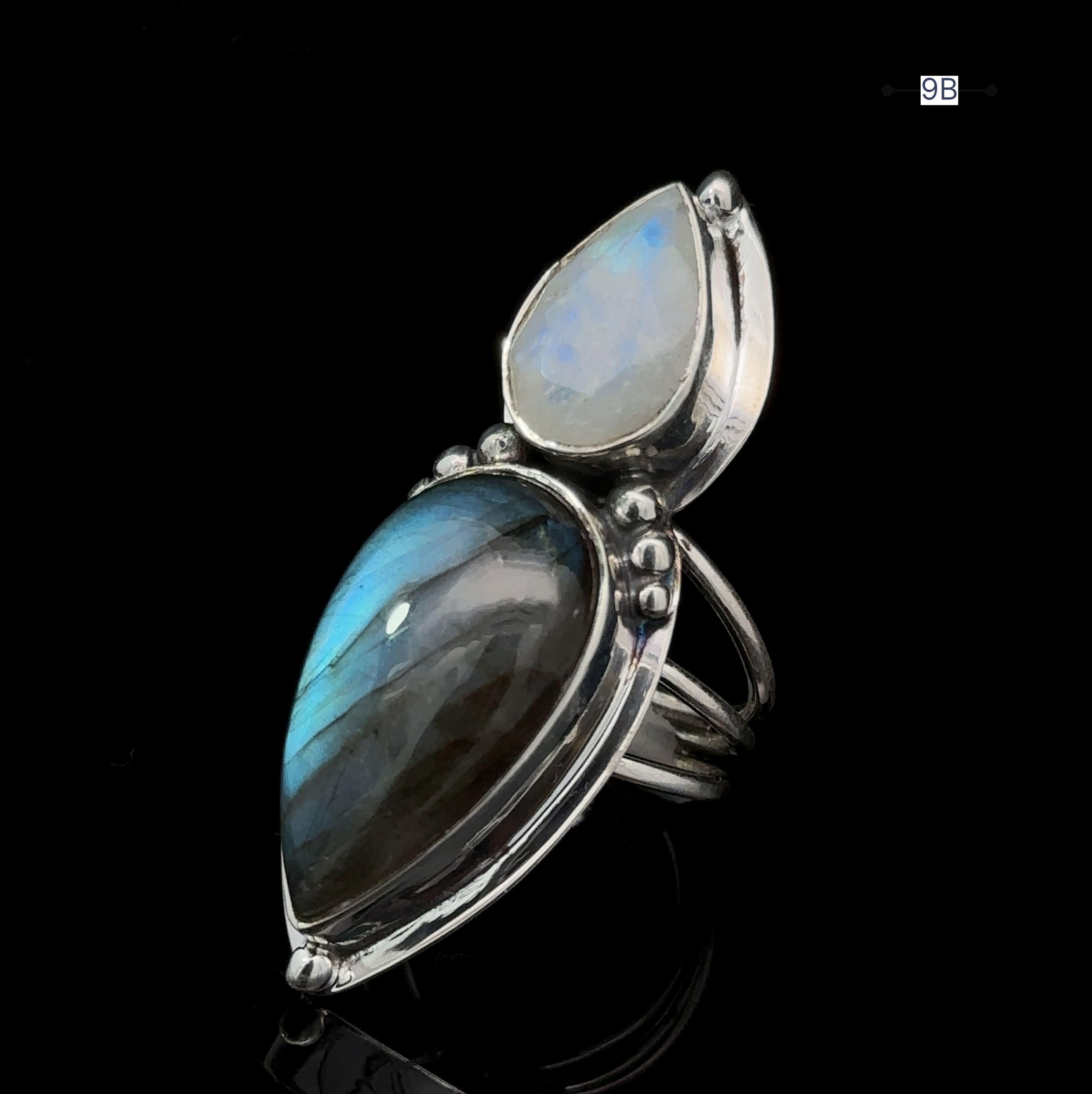 The Heavy Labradorite And Moonstone Ring is a striking silver piece, featuring a large, teardrop-shaped labradorite stone and a smaller pear-shaped moonstone set vertically.