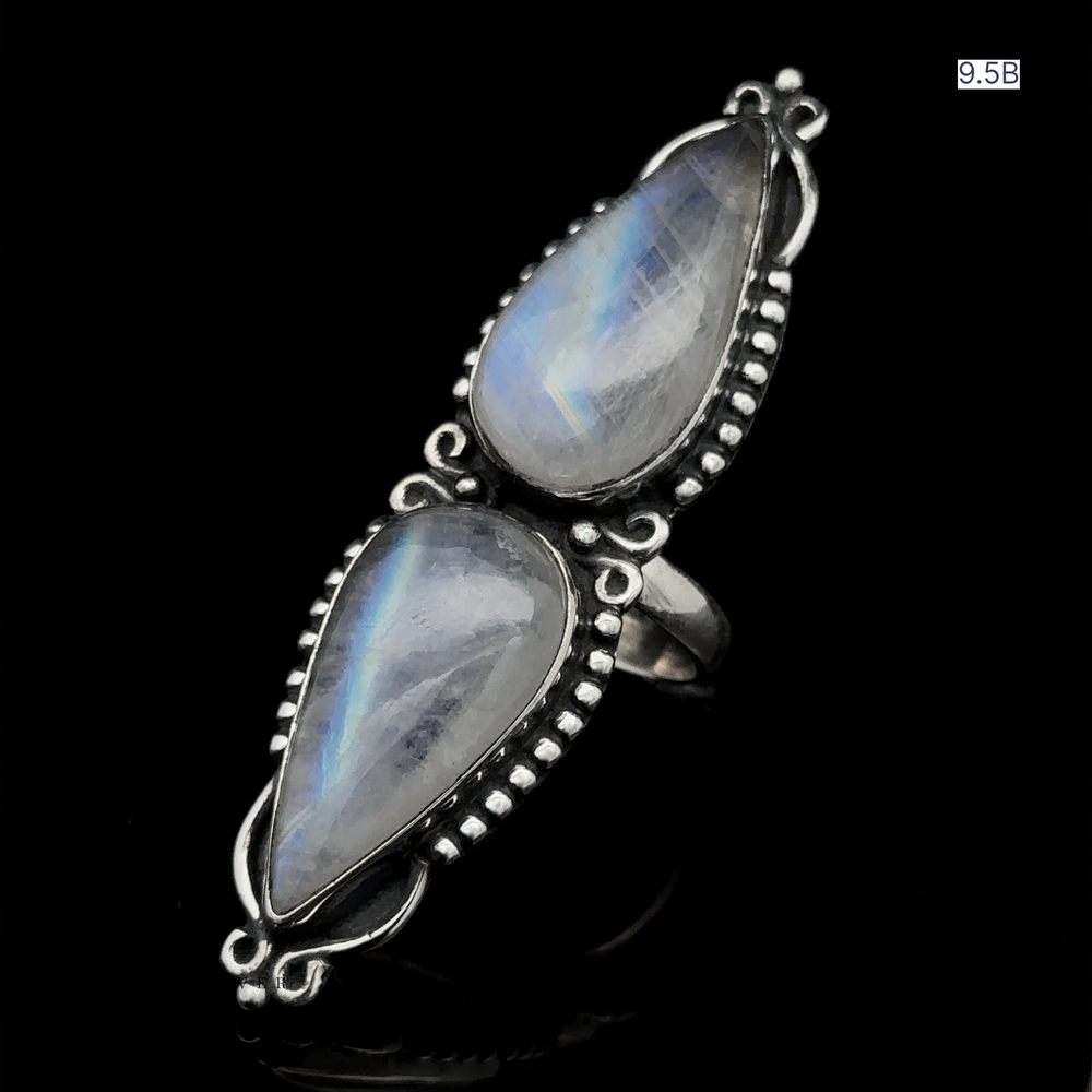 
                  
                    The Long Double Teardrop Moonstone Ring, made of sterling silver and showcasing two teardrop-shaped moonstone gemstones with intricate metalwork, is displayed on a black background with the size "9.5B" noted in the upper corner.
                  
                