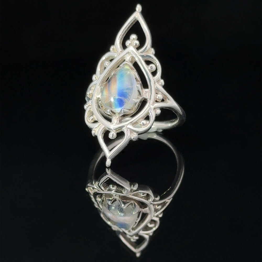 An elegant silver pendant with an Online Only Exclusive Designer Moonstone Ring set in an intricate filigree design, displayed on a reflective black surface.