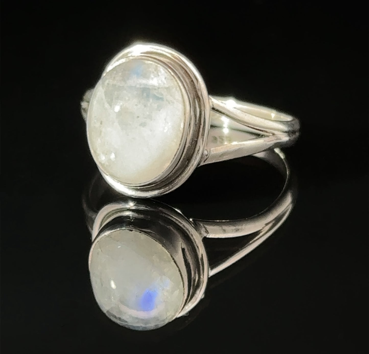 
                  
                    A sterling silver Oval Split Shank Stone Ring with an oval moonstone set on a reflective surface.
                  
                