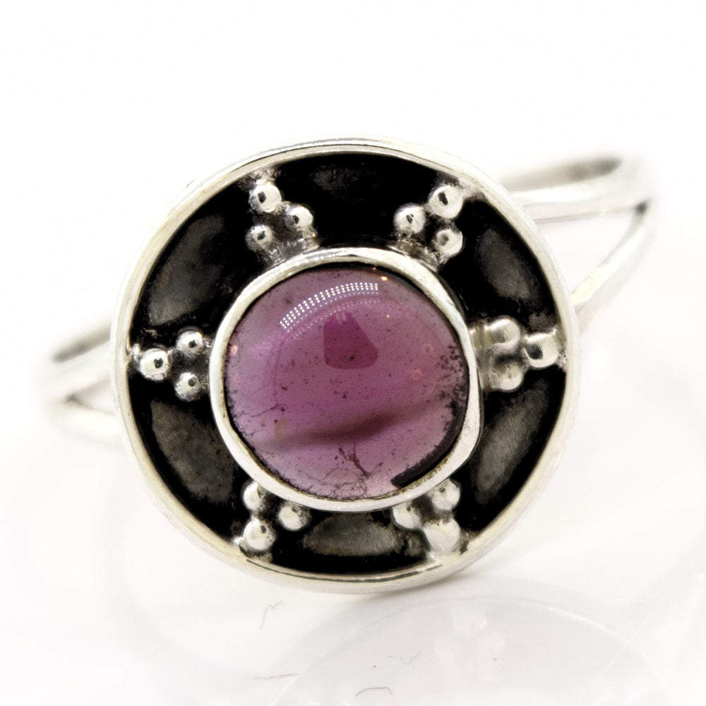 
                  
                    A Gemstone Ring With Unique Oxidized Design features a round purple gemstone set in a circular design with dotted metal embellishments, creating a stunning piece of gemstone jewelry.
                  
                