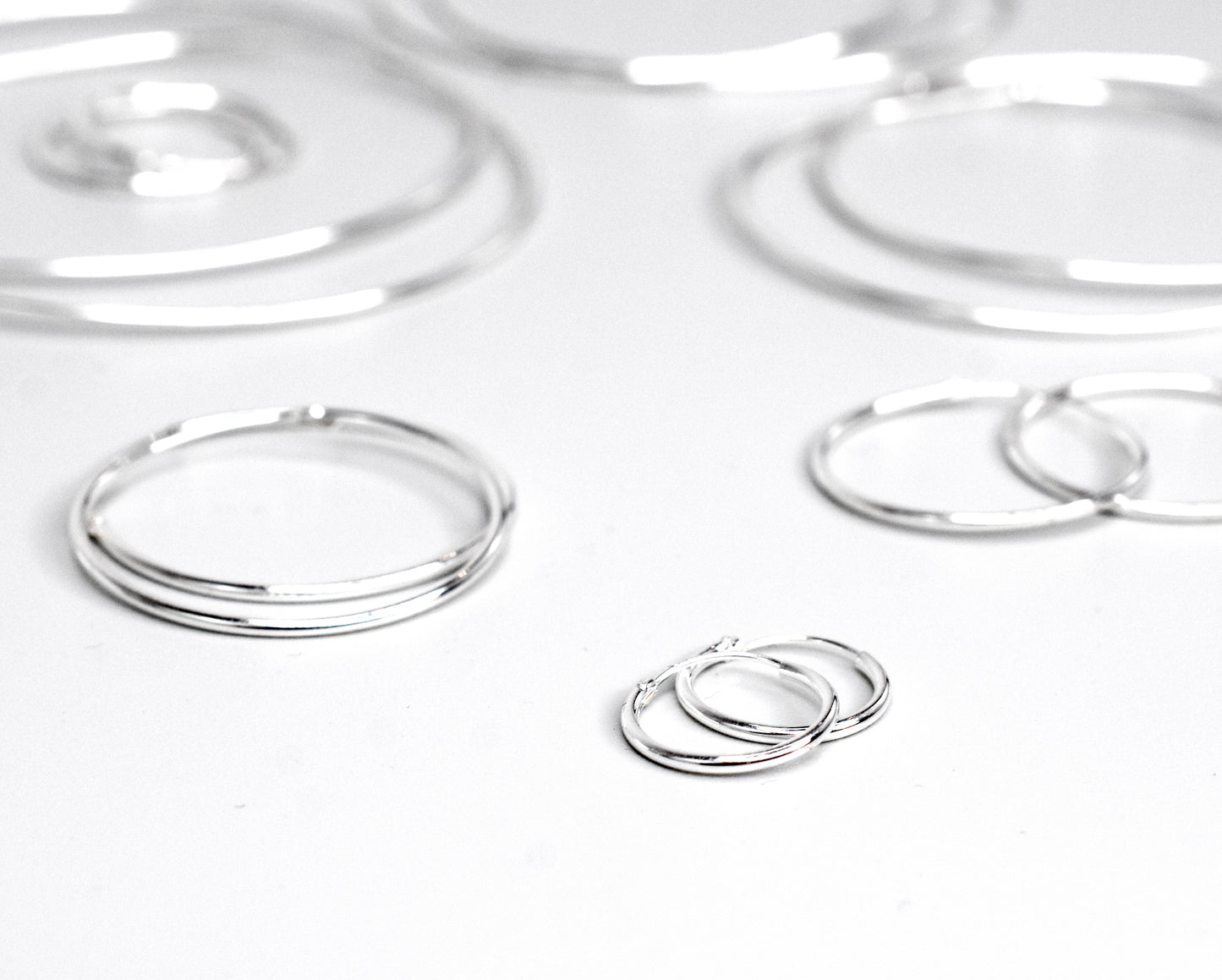 A group of Super Silver's 1.2mm Infinity Hoops on a white surface.