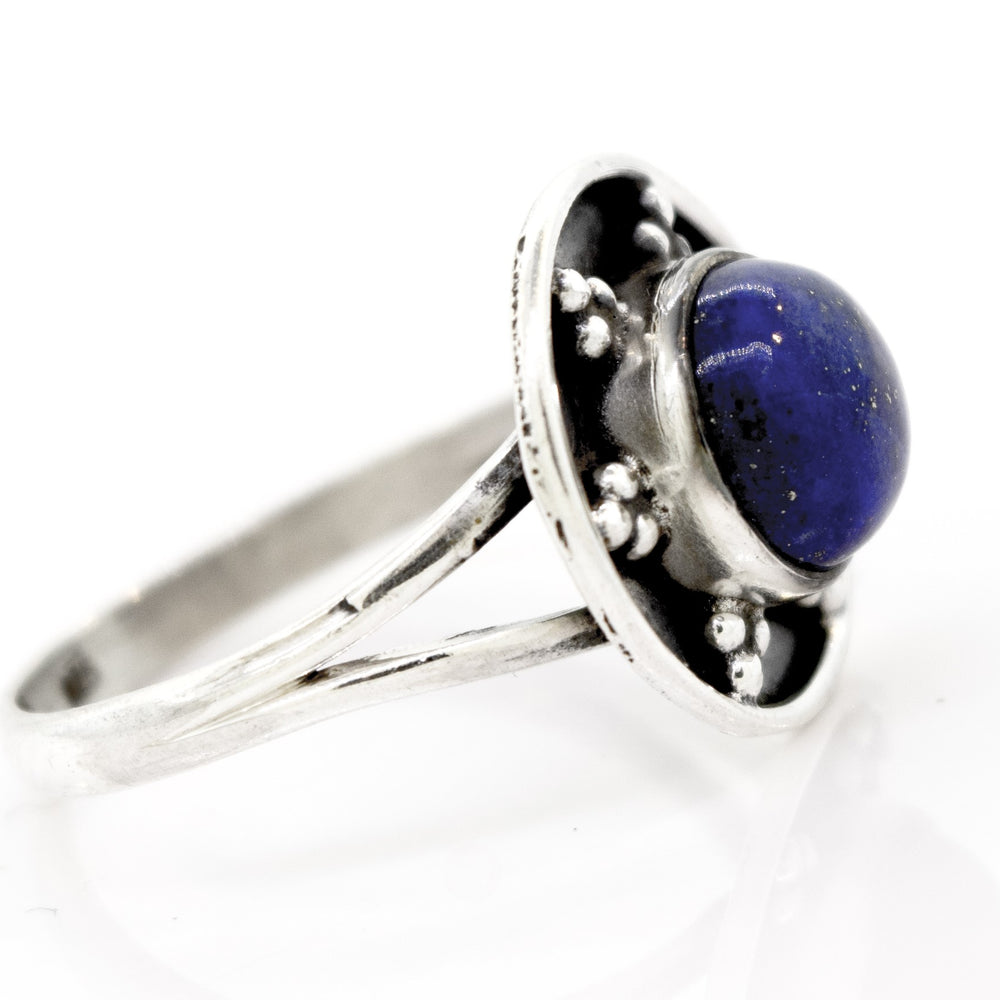 
                  
                    A sterling silver ring with a split shank design features a round blue stone set in a decorative bezel, embodying the essence of the Gemstone Ring With Unique Oxidized Design.
                  
                