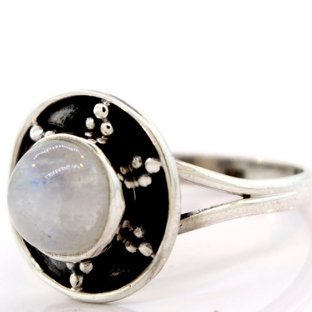 
                  
                    A Gemstone Ring With Unique Oxidized Design featuring a round, polished gemstone at its center, surrounded by a circular black-and-silver oxidized silver setting with small decorative metal dots.
                  
                