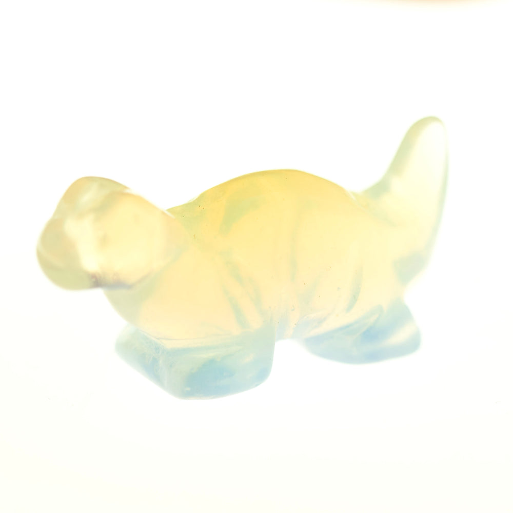 Translucent, small Carved Dinosaur Gemstone Figures in pale yellow and light blue, reminiscent of opalite, photographed against a white background.