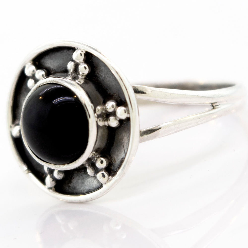 
                  
                    A Gemstone Ring With Unique Oxidized Design featuring a central black stone surrounded by a circular design with metal beads on a white background.
                  
                