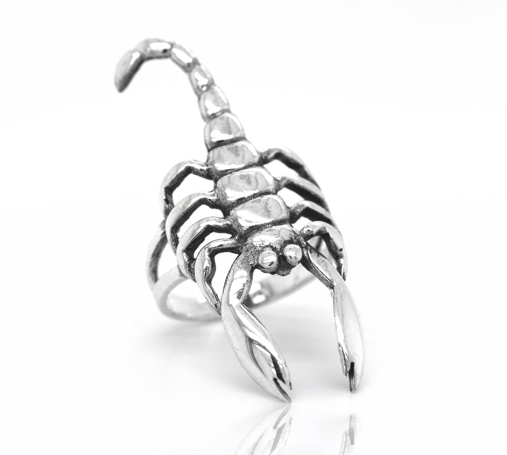 The Striking Scorpion Ring, made from sterling silver with intricate detailing on the legs and pincers, stands upright against a white background.