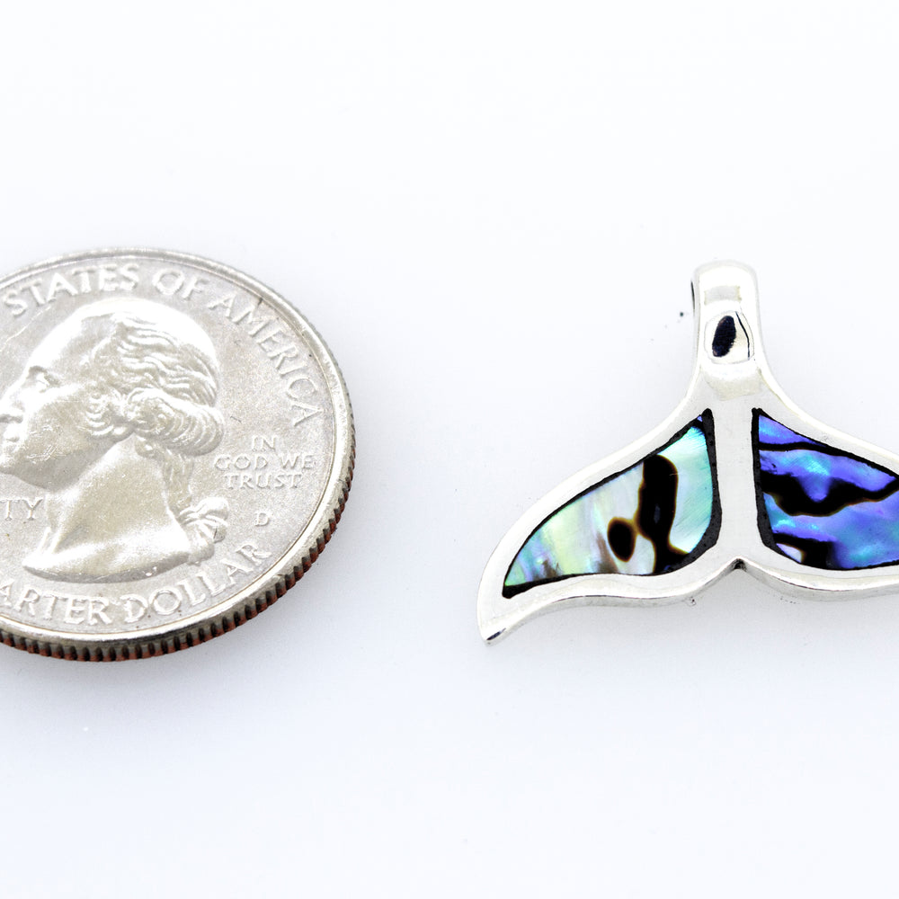 
                  
                    A Super Silver inlay whale tail pendant next to a quarter.
                  
                