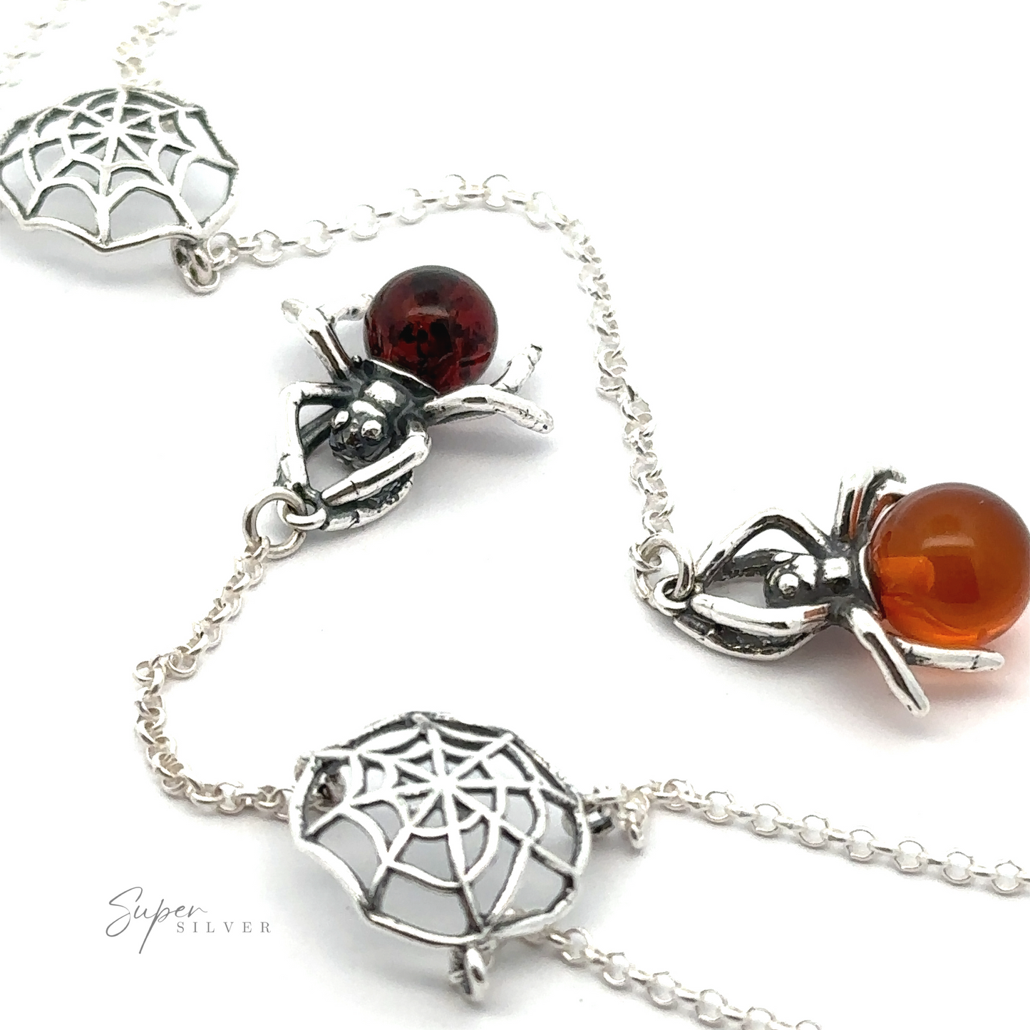 A close-up of a Baltic Amber Spider Necklace featuring spider and spider web designs with red and orange gemstone accents, exuding a witchy vibe. The background is white.