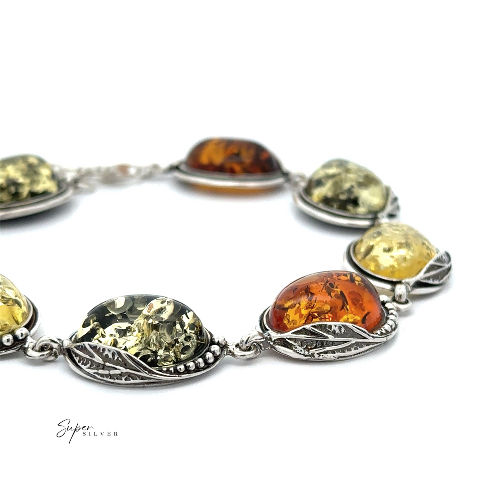 Explore the timeless charm of the Oval Amber Link Bracelet With Leaf Detail. This piece highlights classic elegance with its silver design that elegantly showcases oval amber stones in vibrant shades of green, yellow, and orange against a white background, creating a vintage appeal that enhances any outfit.