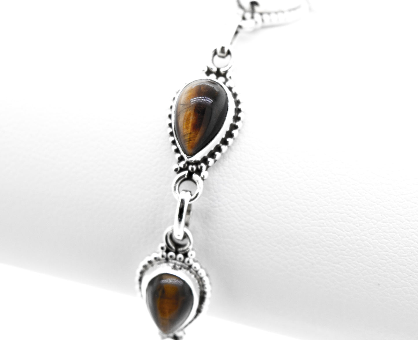 
                  
                    A Teardrop Shape Stone Bracelet With Ball Border featuring tear-shaped tiger's eye gemstones set in .925 silver, attached with circular links, displayed on a white background.
                  
                