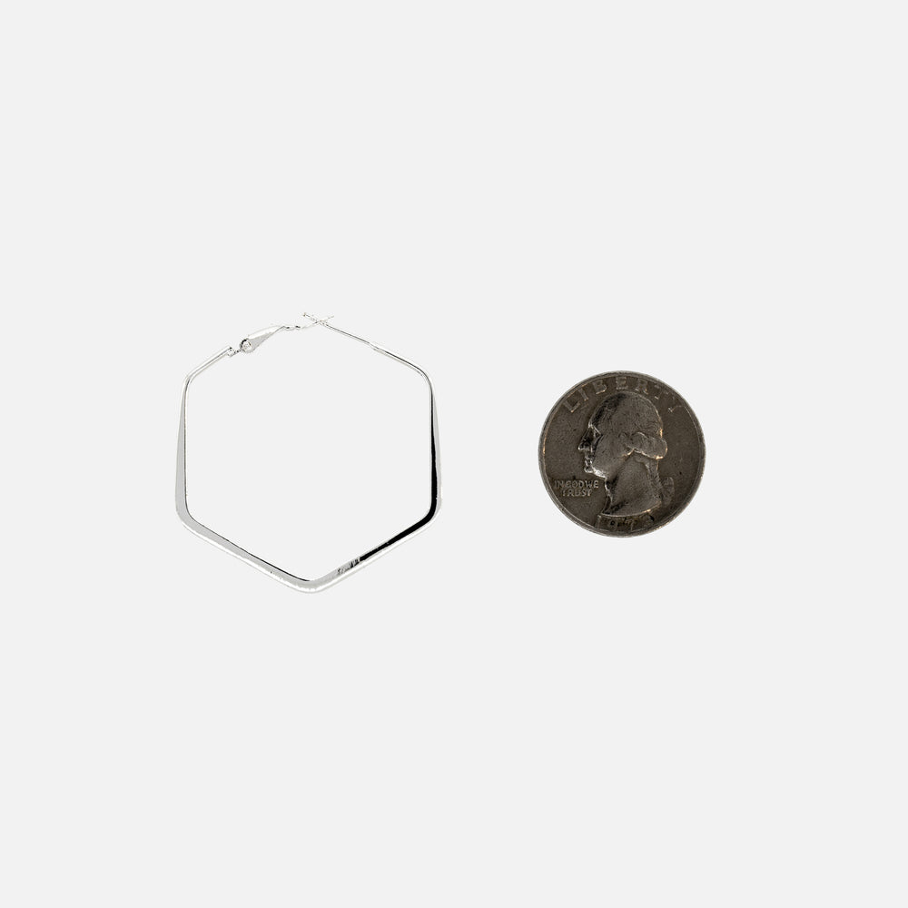 
                  
                    A simple design silver coin next to a Super Silver Flat Hexagon Hinged Hoop earring made of .925 Sterling Silver.
                  
                