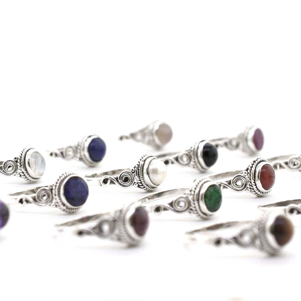 
                  
                    A collection of Gemstone Circle Rings With Rope Border And Swirl Design featuring an array of colorful stone cabochons.
                  
                