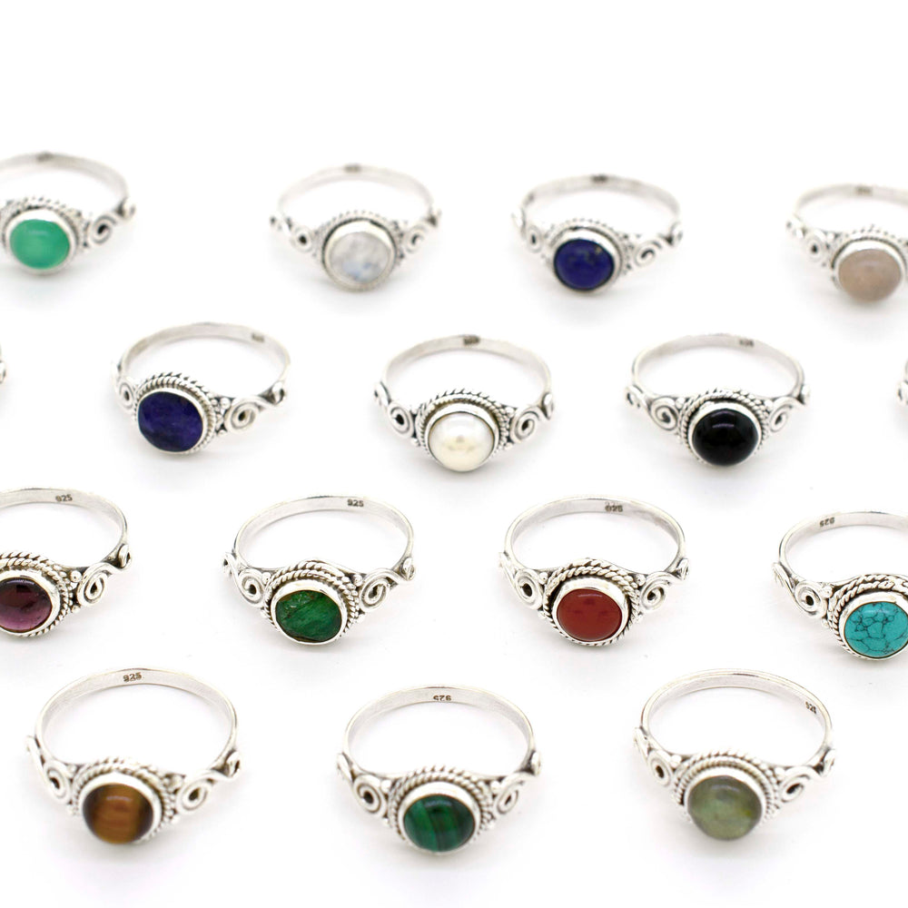 
                  
                    A group of Gemstone Circle Rings With Rope Border And Swirl Design adorned with different colored stones.
                  
                