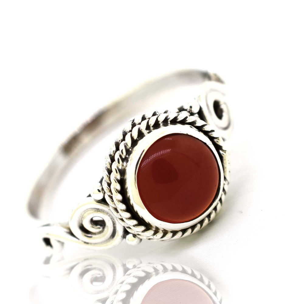 
                  
                    A Gemstone Circle Ring With Rope Border And Swirl Design with a red stone.
                  
                