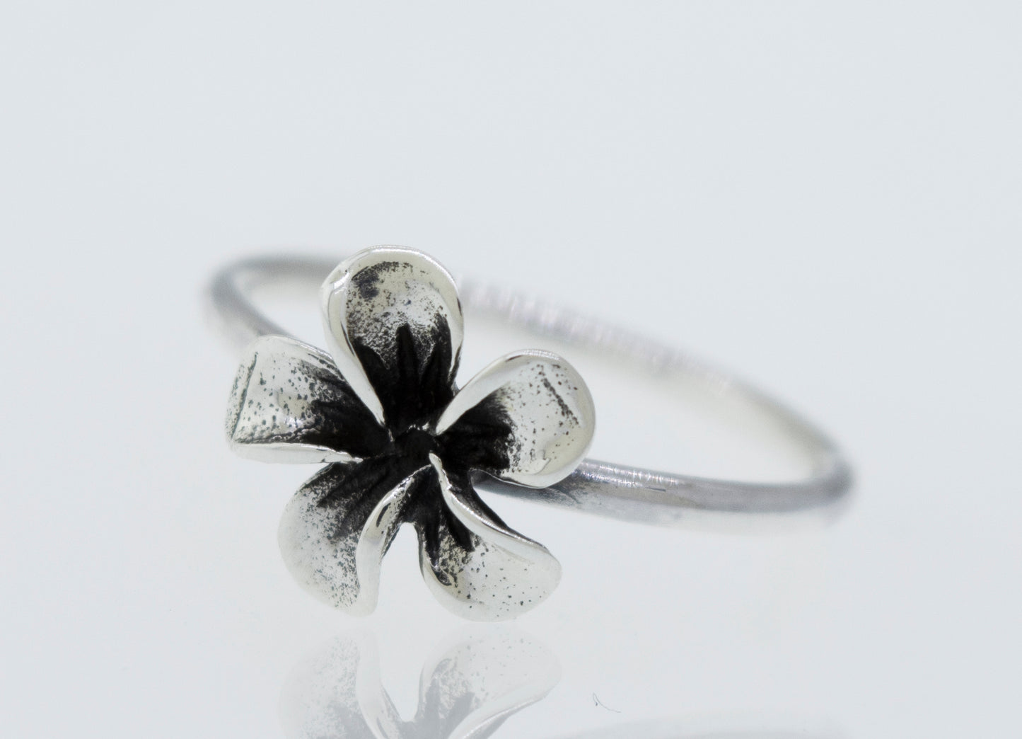 A Plumeria Ring featuring a black and white flower on a white surface.