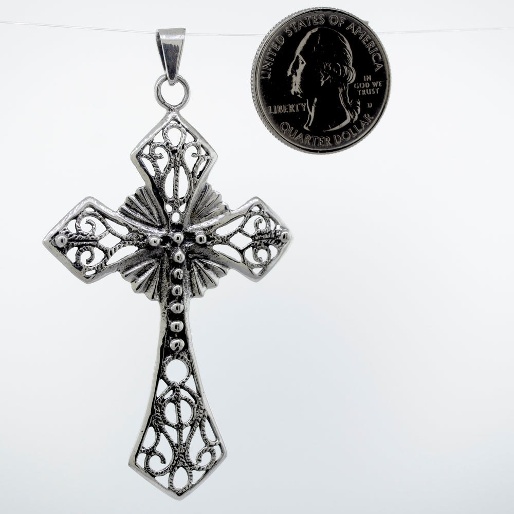 
                  
                    A unique Super Silver Ornate Cross Pendant adorned with intricate silverwork, showcased alongside a dime.
                  
                