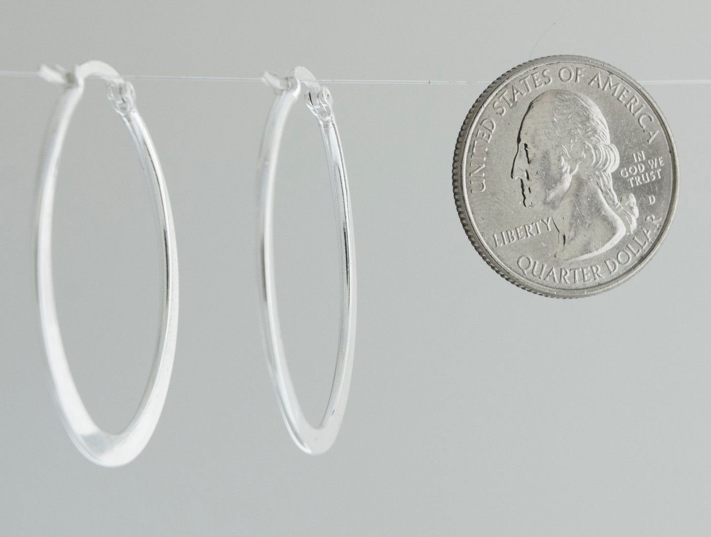 A minimalist Oval Shaped Hoops and coin earrings handcrafted from sterling silver by Super Silver.