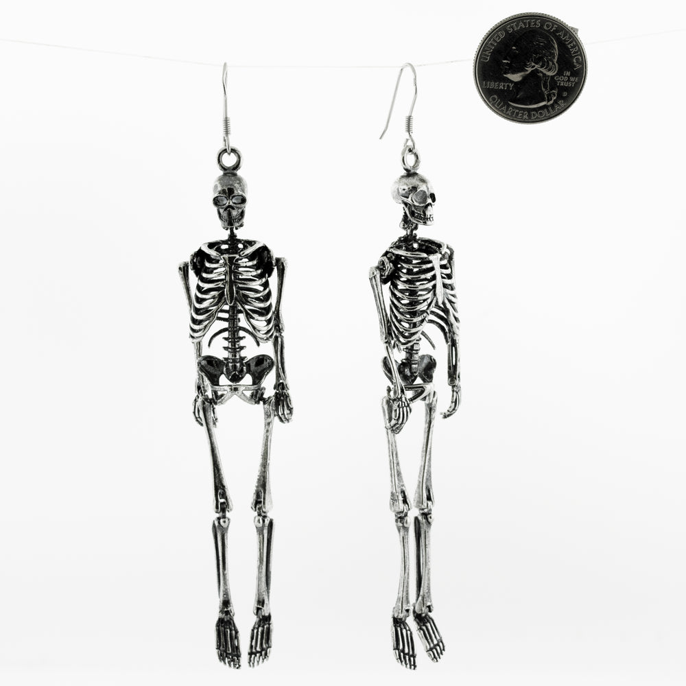 
                  
                    Two Super Silver sterling silver skeleton earrings, hanging on a string.
                  
                