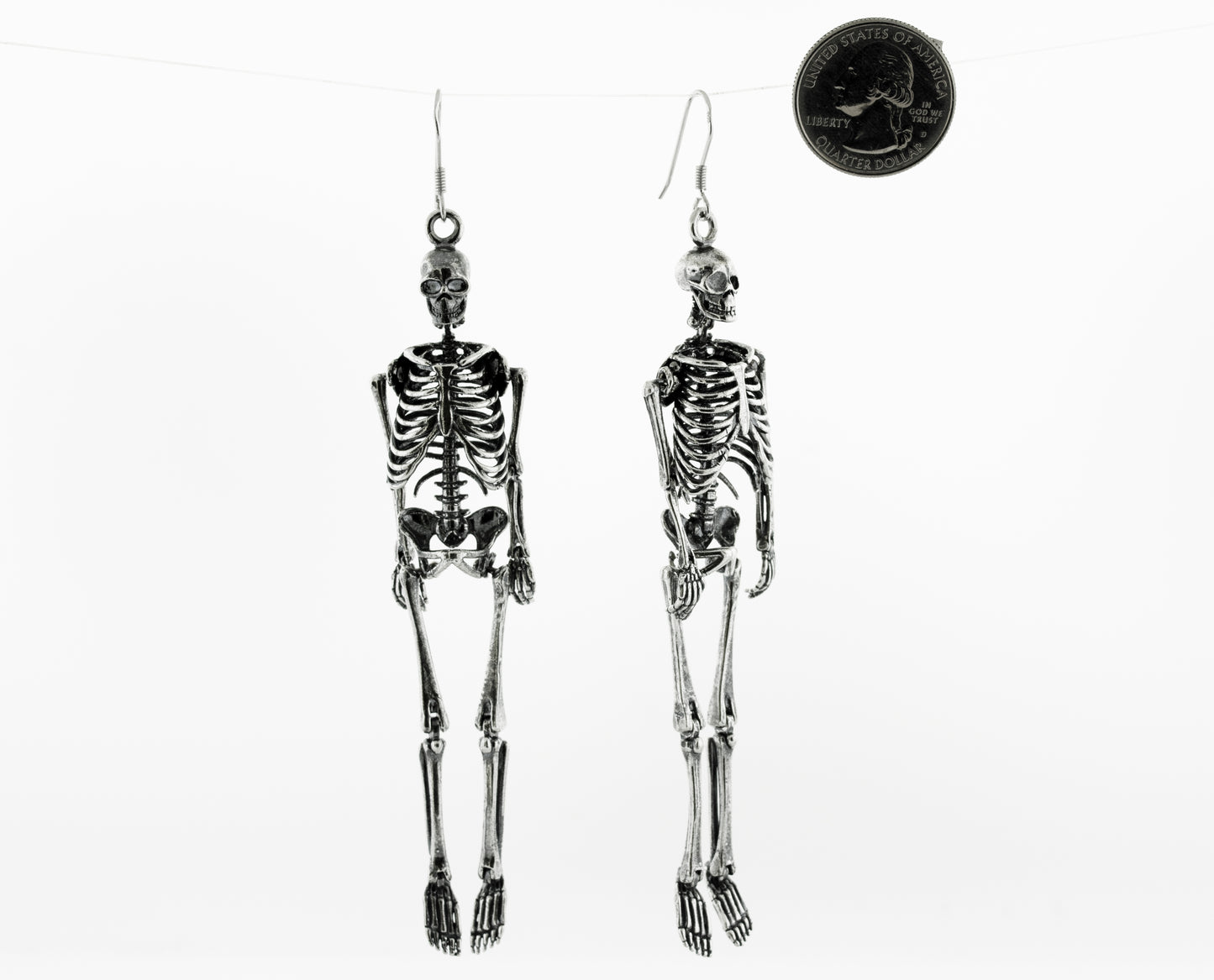 
                  
                    Two Super Silver sterling silver skeleton earrings, hanging on a string.
                  
                