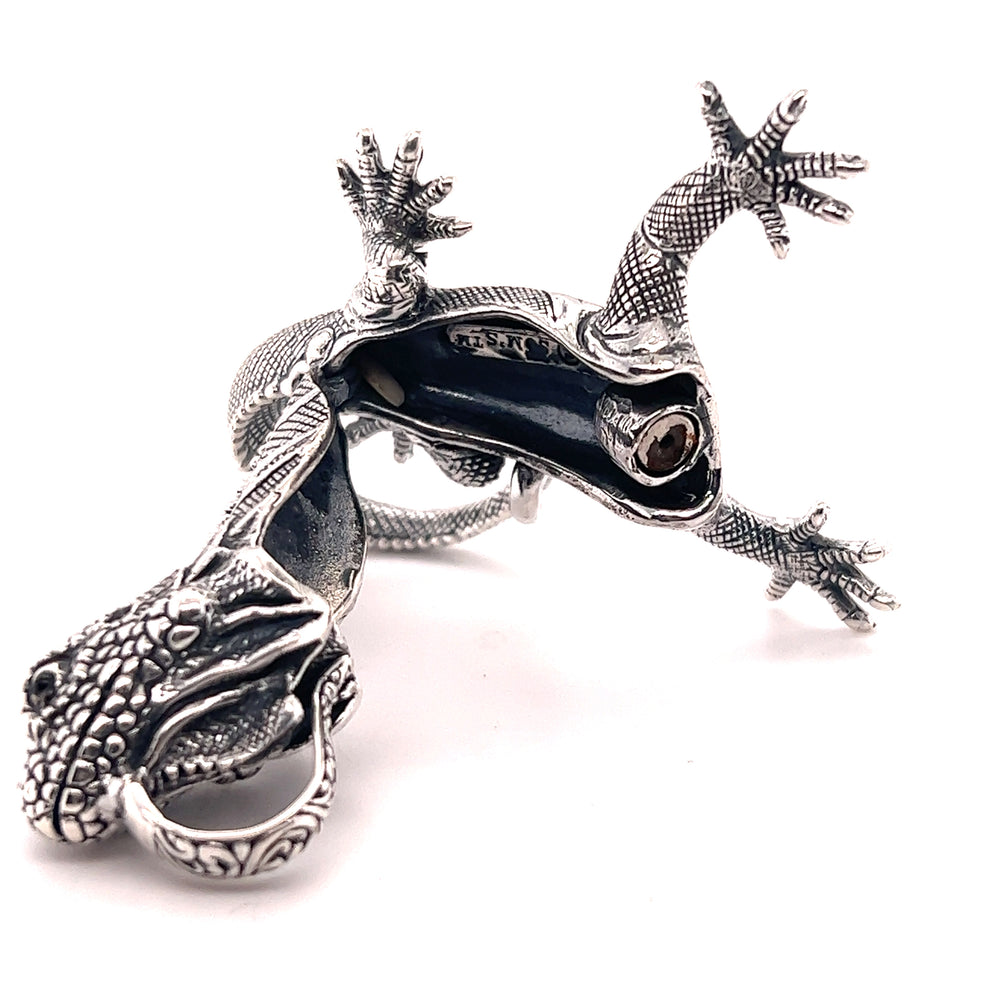 A Super Silver Handcrafted Iguana Pendant, made from .925 Sterling Silver, is laying on a white surface.