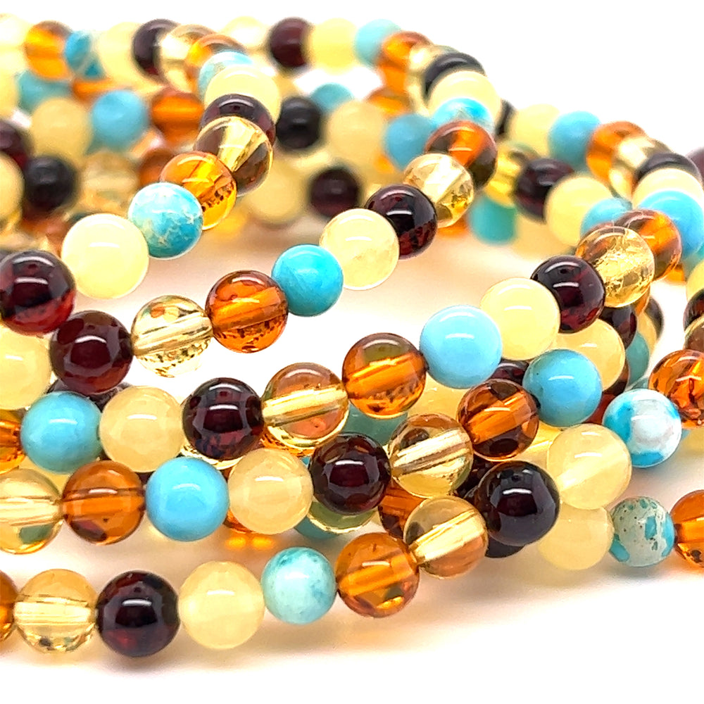 A stack of Multicolored Amber Beaded Bracelet with Turquoise beads on a white surface by Super Silver.