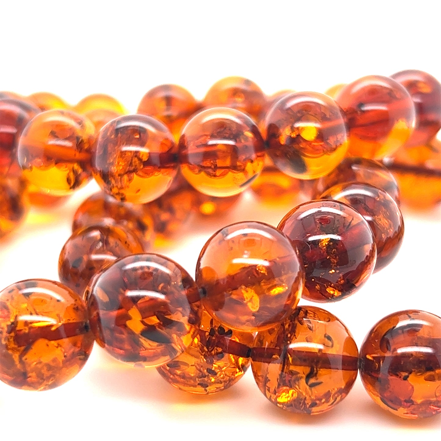 Close-up of the Captivating Classic Amber Bead Bracelet, with its polished Baltic amber beads exhibiting translucent, warm cognac hues and intricate internal patterns beautifully displayed against a white background.