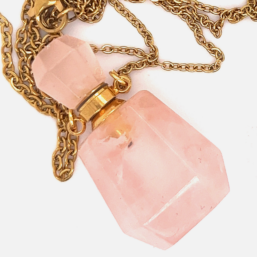
                  
                    A Super Silver Crystal Perfume Vial Necklace adorned with a pink quartz stone, hanging delicately on a gold chain.
                  
                