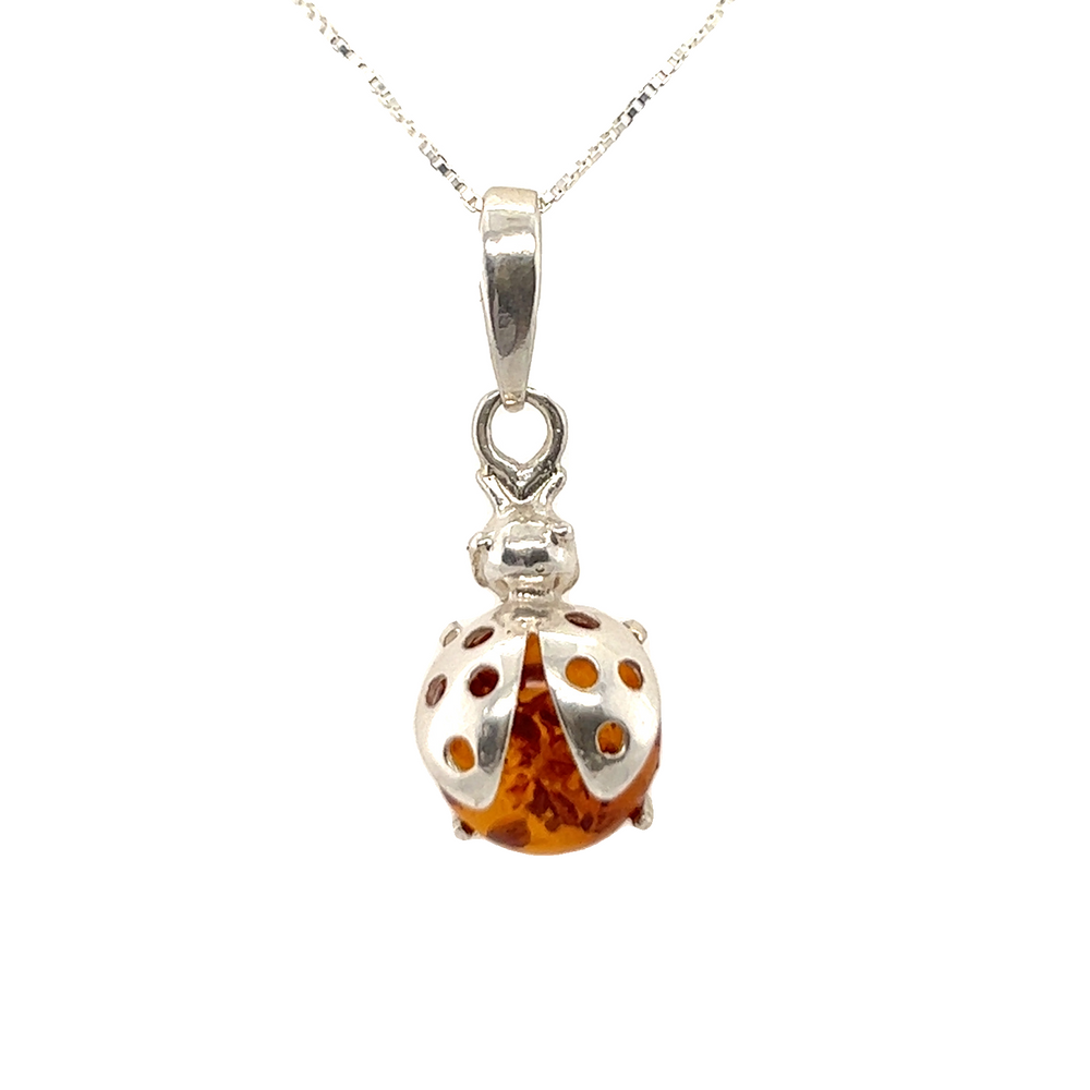 A Super Silver Amber Ladybug Pendant adorned with amber on a delicate silver chain, symbolizing protection.