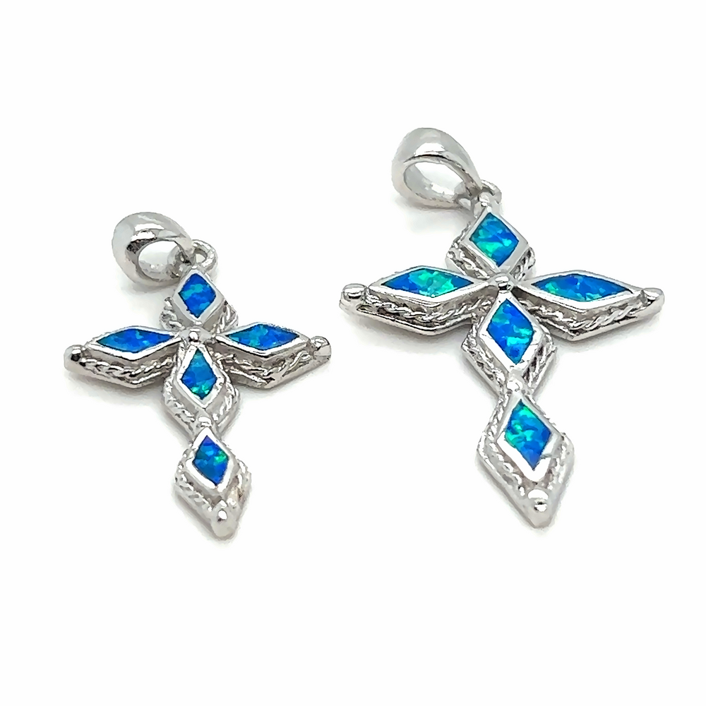 
                  
                    A pair of Super Silver Blue Opal Cross Pendants with a diamond-cut stone and rhodium finish.
                  
                
