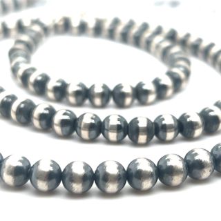 A string of Navajo Pearl Necklace beads with a vintage vibe on a white surface from Super Silver.