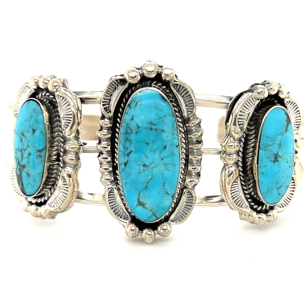 A stunning Super Silver Native American Cuff with Three Stunning Turquoise Stones adorned with exquisite silverwork.