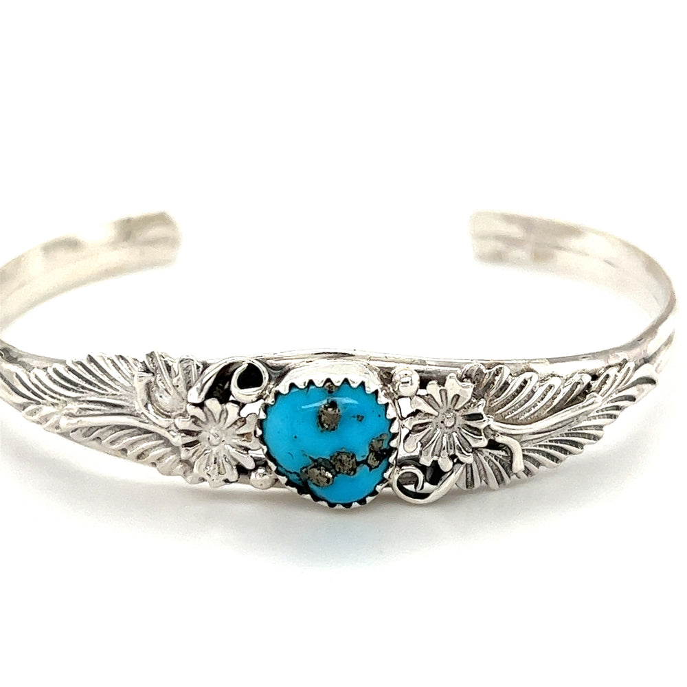 A Super Silver Native American Turquoise Cuff with Floral Designs adorned with a Kingman blue turquoise stone.