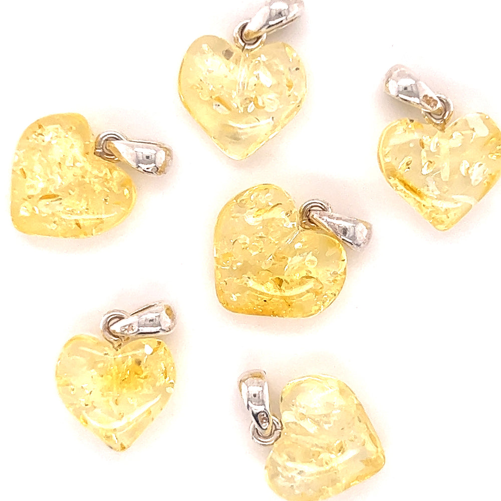 
                  
                    Six yellow glass heart shaped Charming Baltic Amber Heart Pendants with Baltic amber detail on a white background, from the Super Silver brand.
                  
                